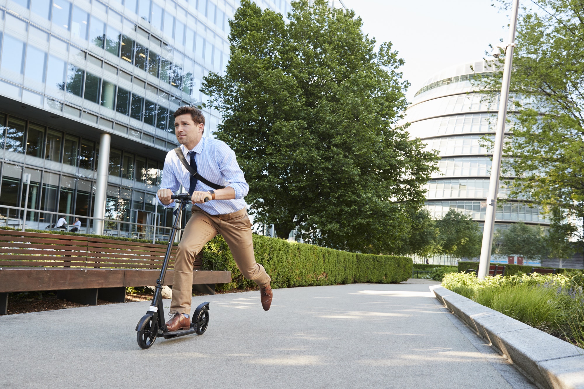 Young Businessman Commuting To Work Through City On Scooter
